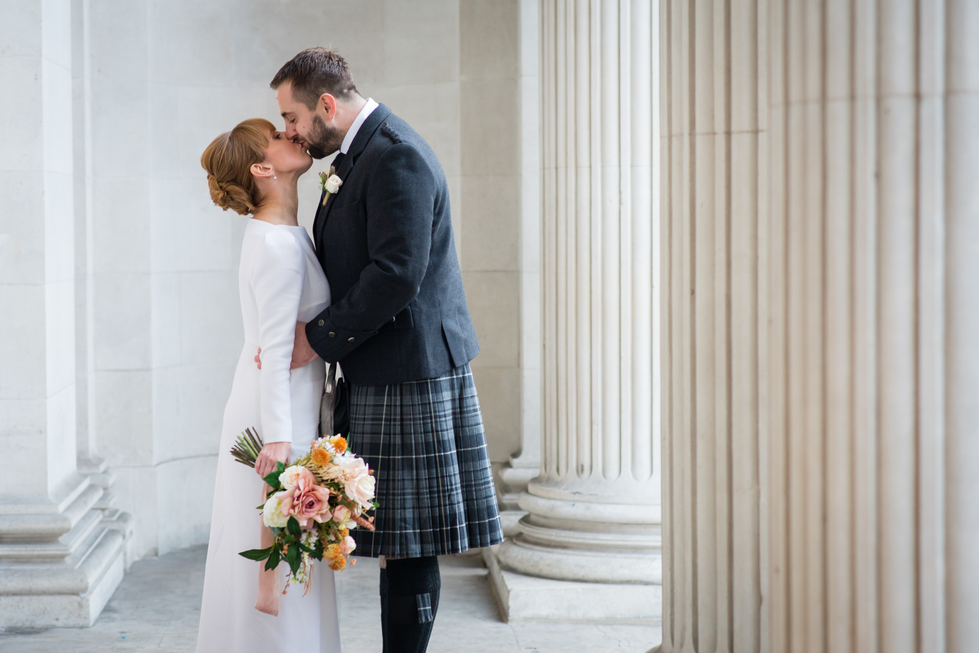 A bride and groom kissing on the steps of Marylebone Town Hall